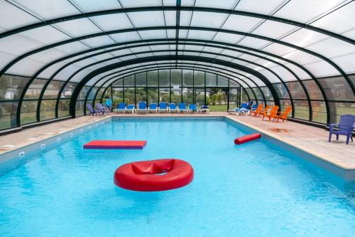 una piscina con techo abovedado y un flotador rojo en el agua en Chalet Jagershut K 6 op park Mooi Oavelt., en Havelte