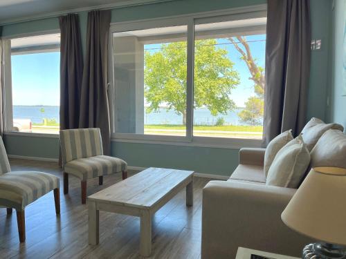 a living room with a couch and a table and windows at Atardeceres Chascomús in Chascomús