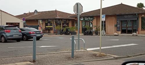 ulica z samochodami zaparkowanymi przed sklepem w obiekcie Votre chaleureux cocon proche Aéroport & Transport w mieście Blagnac