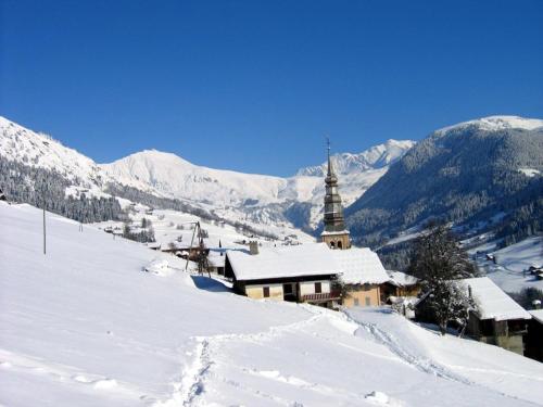 a snow covered hill with a church and a mountain at 40m2 au pied des pistes Hauteluce les saisies 4 à 6 personnes in Hauteluce