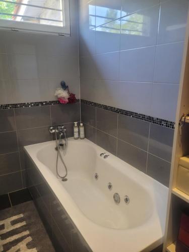 eine weiße Badewanne in einem Badezimmer mit Fenster in der Unterkunft chambre chez hôte in Sainte-Eulalie