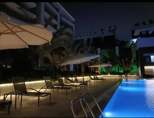 a row of chairs and umbrellas next to a swimming pool at night at Ocean Blue Luxury serviced Hotel Apartments in Cairo