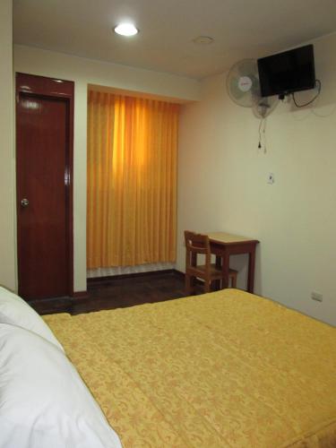a hotel room with a bed and a desk and a television at Hotel Panamericano in Lima