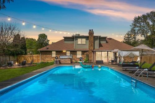a large blue swimming pool in front of a house at Zestlife-LuxuryEscape-ThemedRooms-Pool-GameRoom in Indianapolis