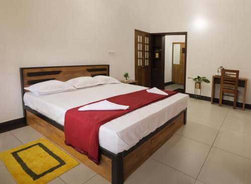 a bedroom with a large bed with a red blanket at Bougainville in Kalpetta