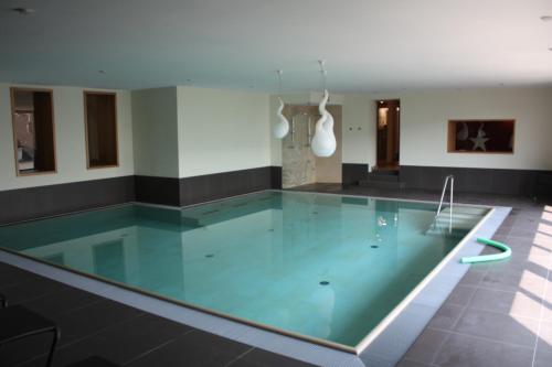 a swimming pool with blue water in a building at WeinBergHotel Nalbach in Reil