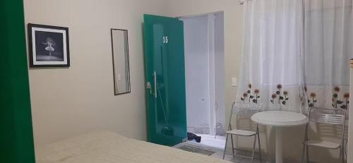 um quarto com uma porta verde e uma mesa e cadeiras em Kitinet Central em Belo Horizonte