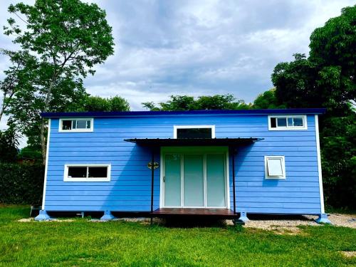 ein blaues Haus mit grüner Tür im Gras in der Unterkunft Tiny House Tauramena in Tauramena