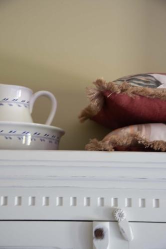 a white shelf with bowls and vases on it at The Cat and The Owl B&B in Groenlo