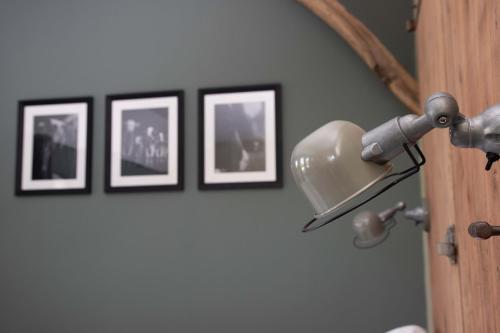 a light on a wall with three framed pictures at The Cat and The Owl B&B in Groenlo