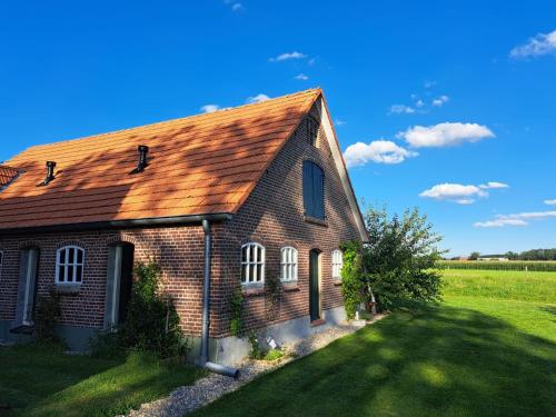 uma velha casa de tijolos num campo de relva em The Cat and The Owl B&B em Groenlo