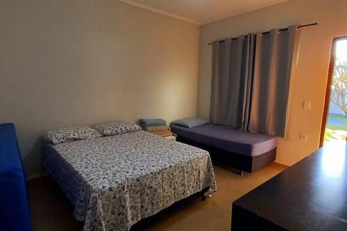 ein Schlafzimmer mit einem Bett, einem Stuhl und einem Fenster in der Unterkunft Chácara p/temporada em Brodowski próx de Rib Preto in Brodósqui