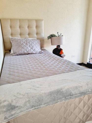 1 cama grande con colcha blanca y lámpara en apartamento equipado, en Amatitlán