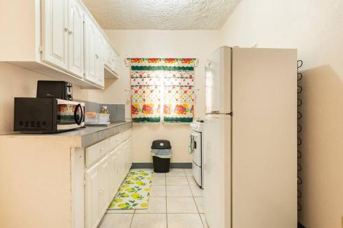 eine Küche mit weißen Schränken und einem Kühlschrank in der Unterkunft Shaw Park Gem Apt 12E in Ocho Rios