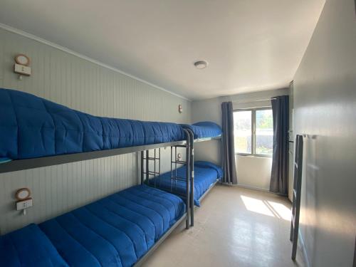2 blaue Etagenbetten in einem Zimmer mit Fenster in der Unterkunft Hostel Cienfuegos in Santiago
