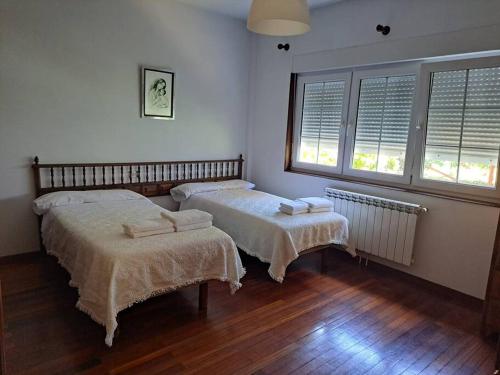 a room with two beds and two windows at Casa Ares in Cee