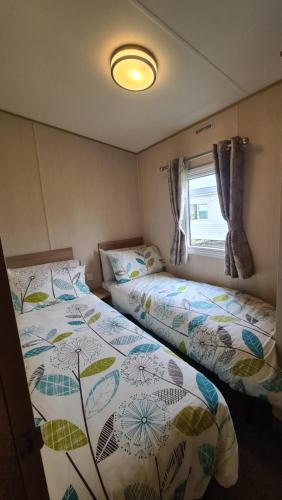 two beds in a small room with a window at 8 Berth Luxury Caravan Butlins Holiday Village Skegness in Skegness