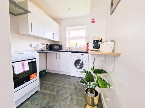a kitchen with a washing machine and a plant in it at 1 Bed Central Serviced Accommodation with Balcony in Stevenage Free WIFI by Stay Local Home Welcome Contractors Business Travellers Families in Stevenage