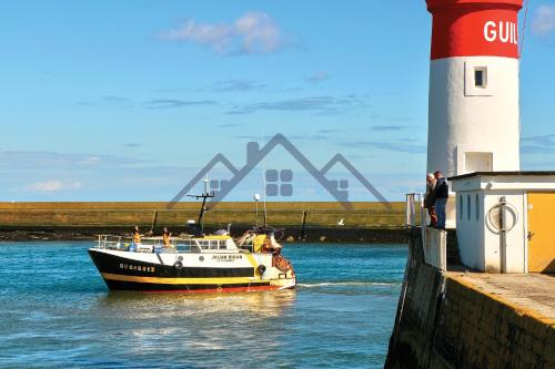 a boat in the water next to a lighthouse at LocaLise - M3C - La petite Bigoudène - Maison entièrement rénovée en duplex avec jardin - Tout à pied, plage, port, centre, commerces - Wifi inclus - Draps inclus - Animaux bienvenus in Le Guilvinec
