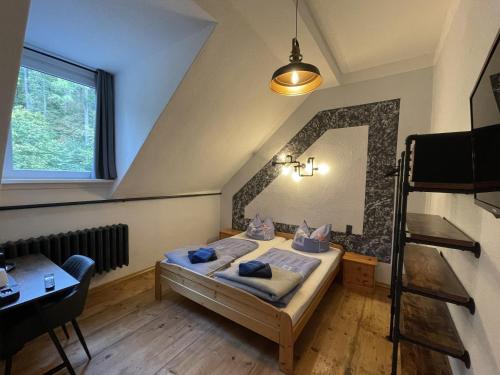 a bedroom with a bed and a desk and a window at Hotel Mühlental in Wernigerode