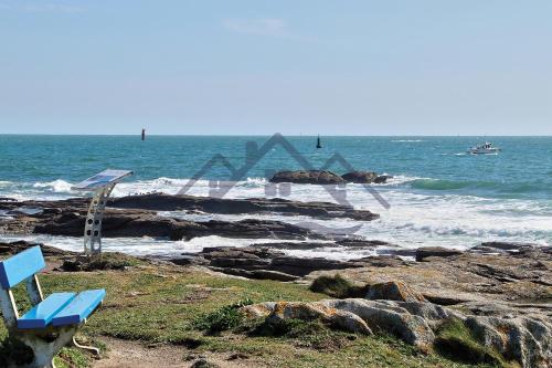 a blue bench sitting on the beach near the ocean at LocaLise - M3C - La petite Bigoudène - Maison entièrement rénovée en duplex avec jardin - Tout à pied, plage, port, centre, commerces - Wifi inclus - Draps inclus - Animaux bienvenus in Le Guilvinec