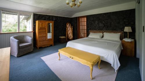 a bedroom with a large bed and a chair at Cobblestone Cottages in Sharbot Lake