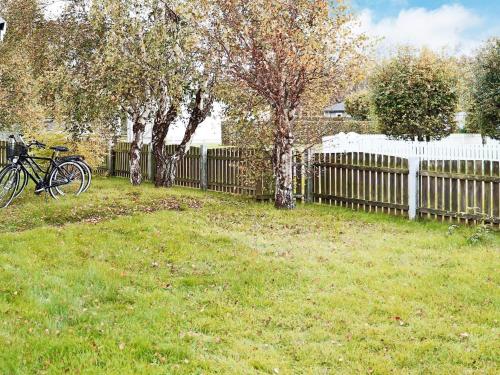 a fence in a yard with a bike parked in the grass at 6 person holiday home in LAHOLM-By Traum in Laholm