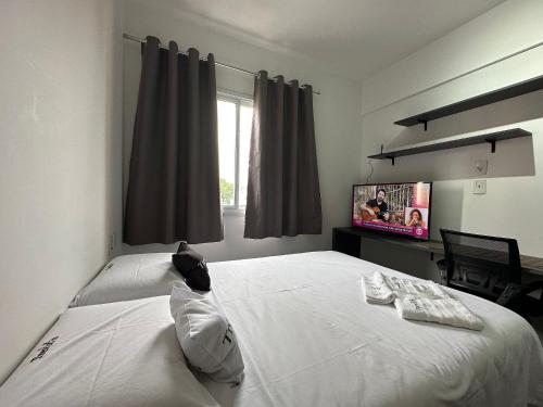 a bedroom with a large white bed and a tv at TrevizZo São Caetano do Sul in São Caetano do Sul