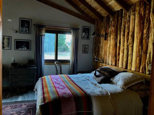 a bedroom with a large bed with a wooden wall at Donde la Carmelita in Melipeuco