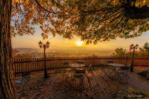 a table and chairs with a sunset in the background at Berggasthof Koitsche im Naturpark Zittauer Gebirge in Bertsdorf