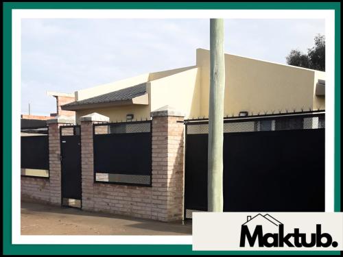 a building with a fence and a pole in front of it at Maktub Alojamiento in San Antonio Oeste