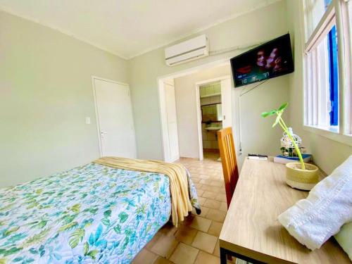 a bedroom with a bed and a table and a tv at Garden 437 Suítes in Florianópolis