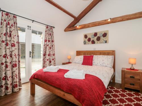 a bedroom with a bed with a red blanket at Poppy Cottage in Cowbridge