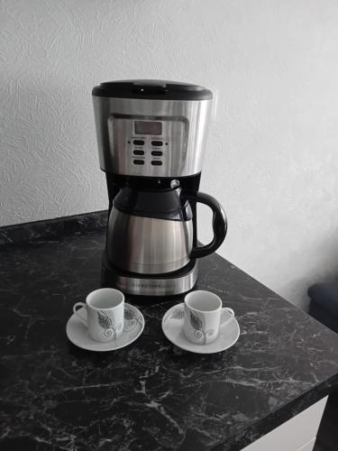 una cafetera y dos tazas en un mostrador en Monte Cristo, en Metz