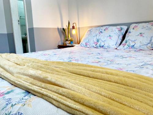 a bed with a gold blanket on top of it at Garden 437 Suítes in Florianópolis