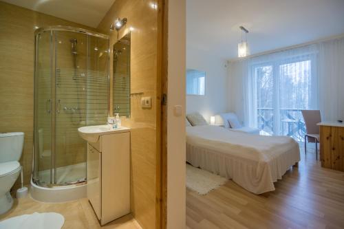 a bedroom with a bed and a bathroom with a shower at Pensjonat Magdalena in Szklarska Poręba
