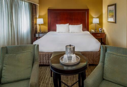 a hotel room with a bed and two chairs at Crowne Plaza Hotel St. Louis Airport by IHG in Bridgeton
