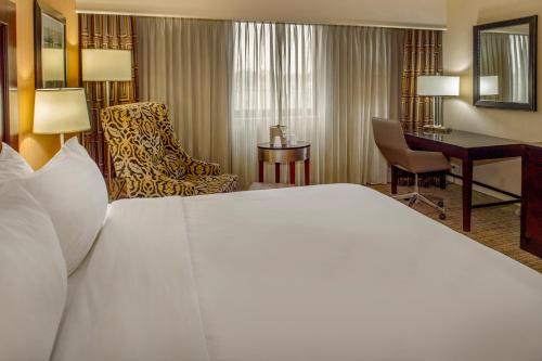 a hotel room with a large white bed and a desk at Crowne Plaza Hotel St. Louis Airport by IHG in Bridgeton