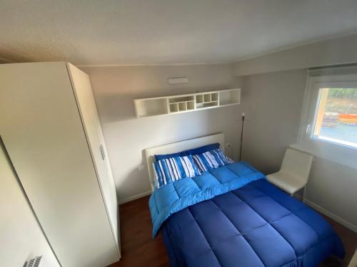 a small bedroom with a blue bed and a window at Tonale 5 min Dagli Impianti Da Sci in Passo del Tonale