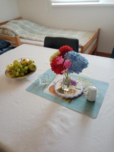 a table with a vase of flowers and a plate of fruit at Azra in Visoko