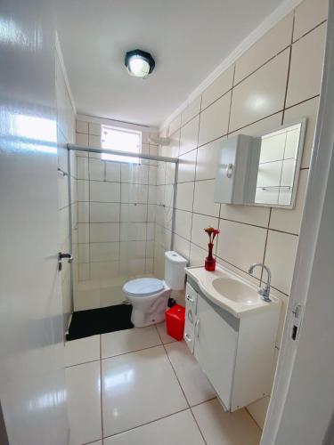 a white bathroom with a toilet and a sink at Hotel Alexandria in Batatais