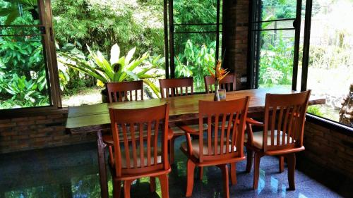 a wooden table and chairs in a room with windows at Hotel Khaosok and Spa in Khao Sok