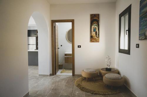 un corridoio con due sgabelli, un tavolo e uno specchio di Villa des deux oliviers Djerba a Djerba