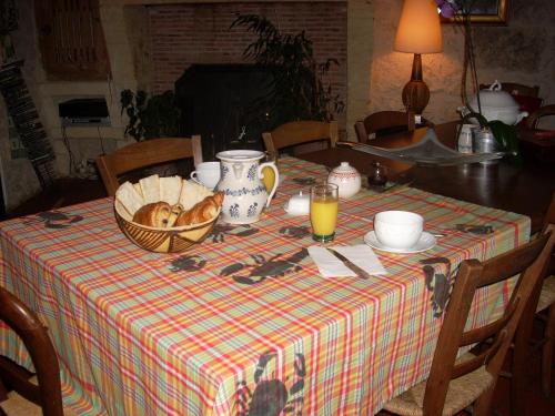 a table with a table cloth with a basket of bread at Sous les Marronniers in Petit-Palais-et-Cornemps