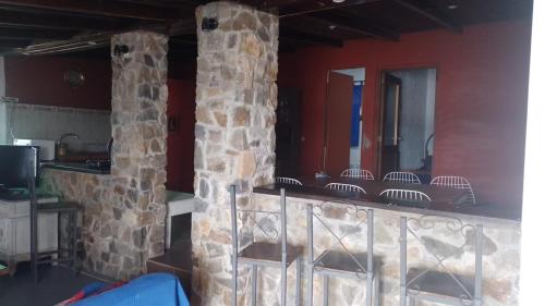 Habitación con pared de piedra y barra con sillas. en Buena Vista, en Salto
