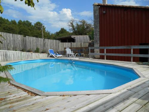 a swimming pool in a backyard with a wooden deck at Sous les Marronniers in Petit-Palais-et-Cornemps