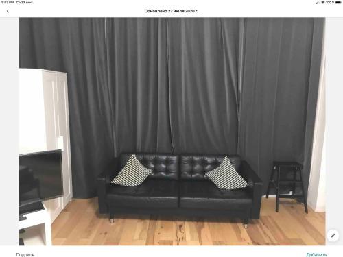a black couch with two pillows in front of a curtain at Brooklyn Beach Location in Brooklyn