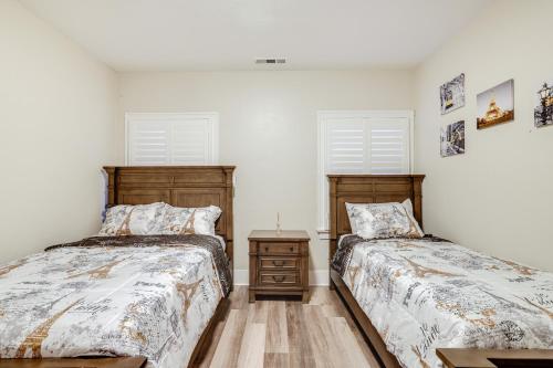 2 camas en una habitación con paredes blancas y 2 ventanas en Sunny Turlock Cottage Walk to Downtown!, en Turlock