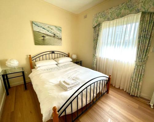 a bedroom with a bed with white sheets and a window at Baywater in Kingscote
