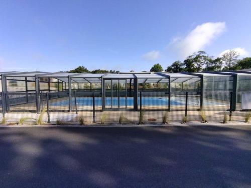 une clôture avec une piscine derrière un bâtiment dans l'établissement Cottage Nature Piscine partagée Vue Vilaine, à Arzal